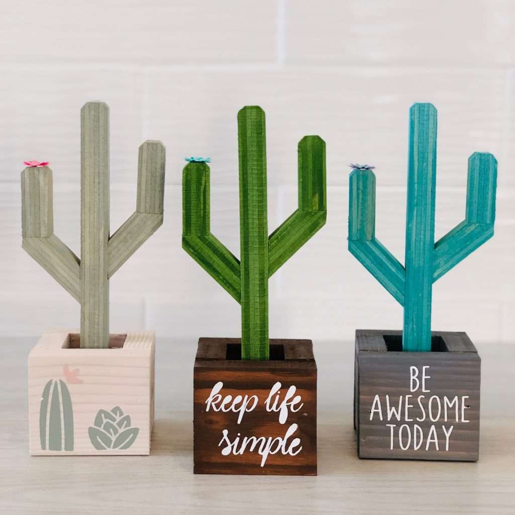 wooden cacti in boxes, one has cacti painted in the front, one says keep life simple and one says be awesome today