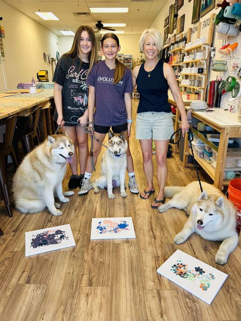 3 paw-casso paintings created by 3 huskies, posing along with their mom and nieces