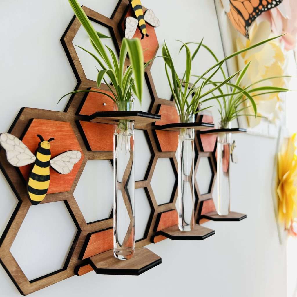 Side view of the Buzz and Grow Plant Propagation Station. Wooden honeycomb with 3 test tubes holding spider plant pups for propagation